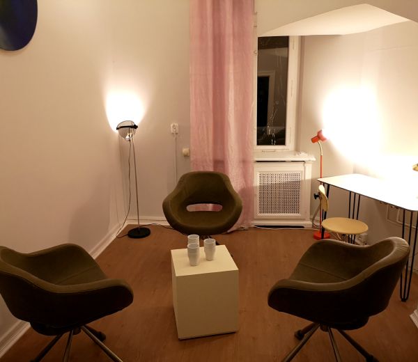 Praxisraum von Monica Burger am Kurfürstendamm in Berlin: drei Sessel im Kreis, Schreibtisch und warmes Licht